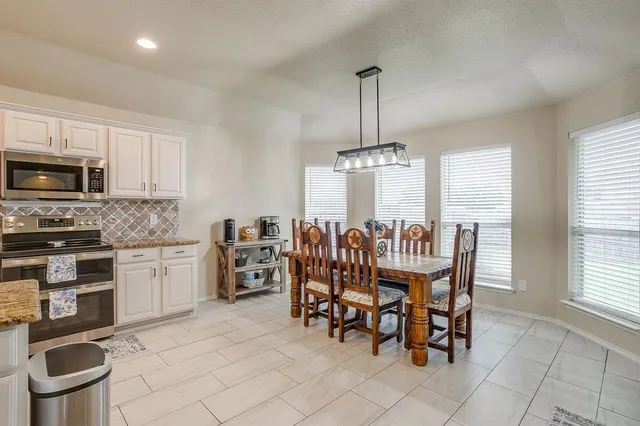 a dining room with furniture a chandelier and kitchen view