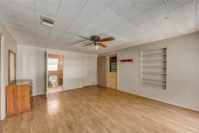 a view of empty room with wooden floor and ceiling fan