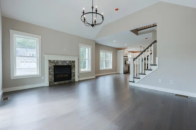 a view of an empty room with wooden floor fireplace and a window