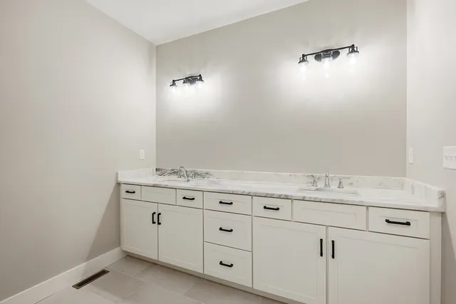 a bathroom with a granite countertop sink and white cabinets