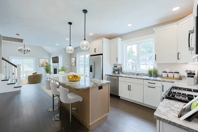 a kitchen with granite countertop a stove a sink a dining table and chairs
