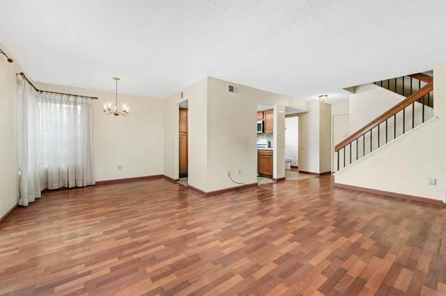 a view of an empty room with wooden floor and white walls