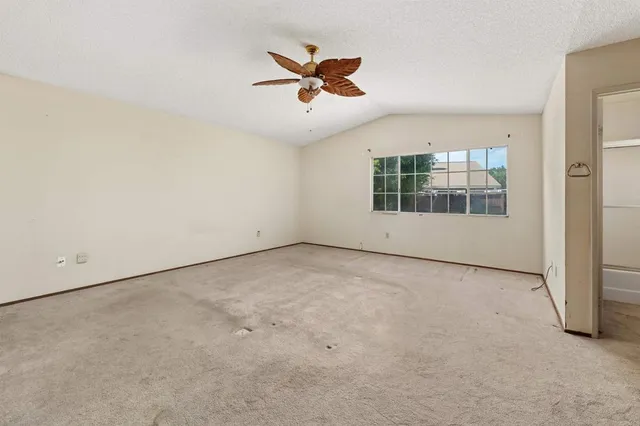 an empty room with windows and ceiling fan