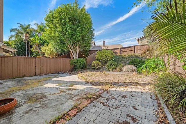 a backyard of a house with plants and trees with wooden fence