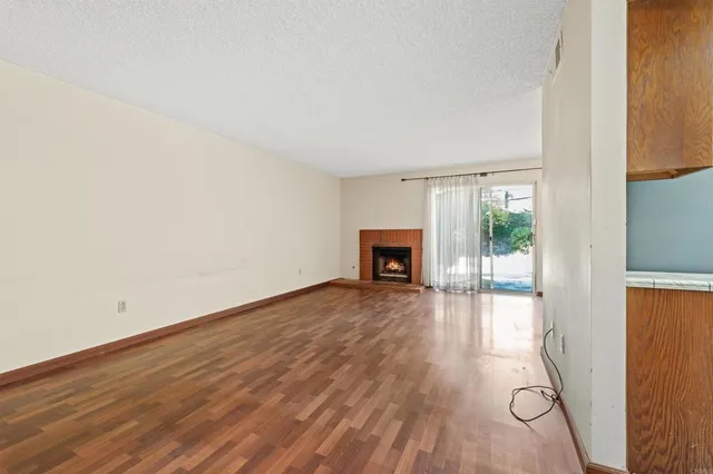 a view of empty room with wooden floor and fireplace