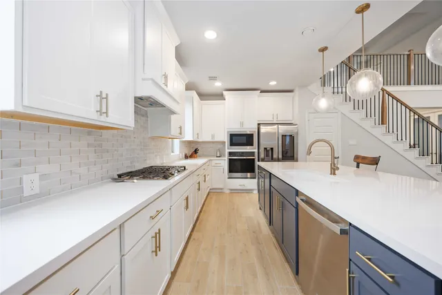 a large kitchen with stainless steel appliances granite countertop a sink a stove and a refrigerator