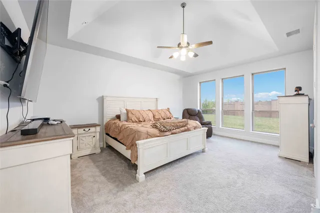 a spacious bedroom with a bed and a flat screen tv