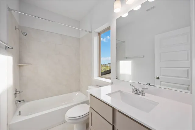 a bathroom with a bathtub shower sink vanity mirror and toilet