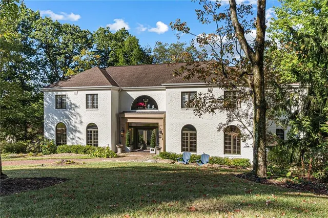 a view of white house with a big yard and large trees