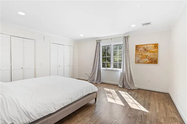 a spacious bedroom with a bed and wooden floor