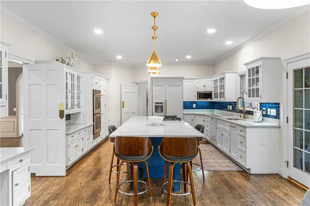 a kitchen with stainless steel appliances kitchen island granite countertop a dining table chairs and white cabinets