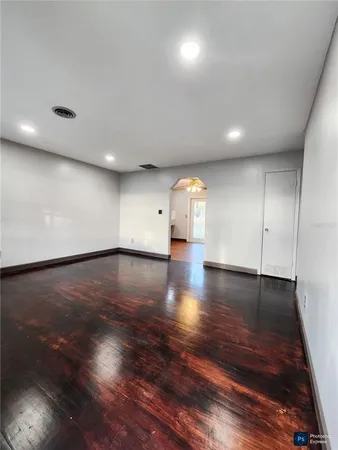 a view of an empty room with wooden floor and a window