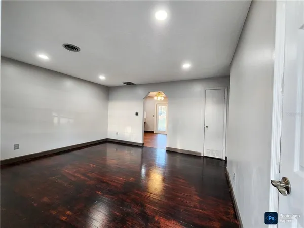 an empty room with wooden floor and windows