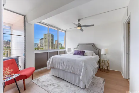 a bedroom with a bed a chair and a large window