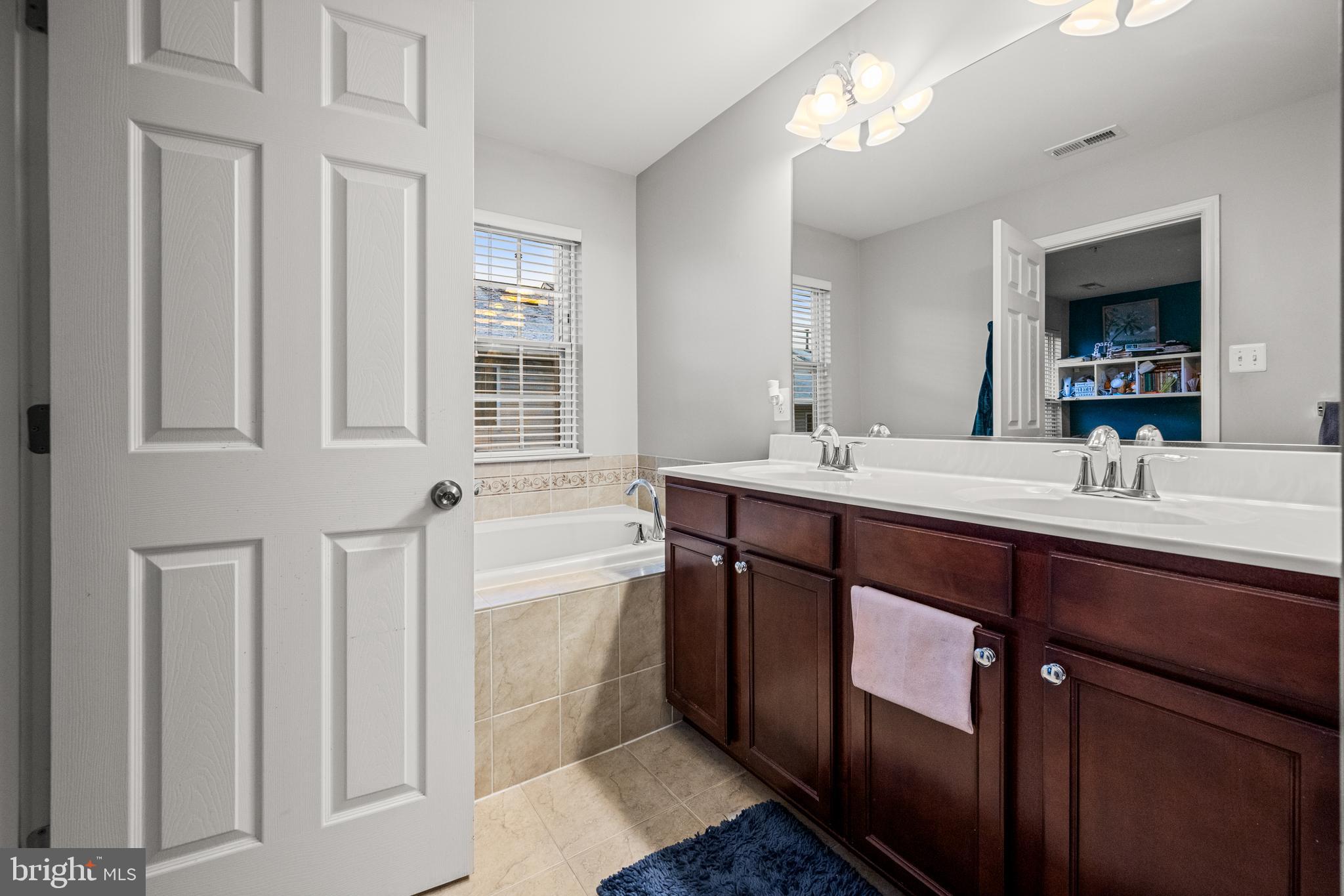 8020 Wright Place Shady Side, MD 20764 - Photo 15 of 21 a bathroom with a double vanity sink a large mirror and a bathtub