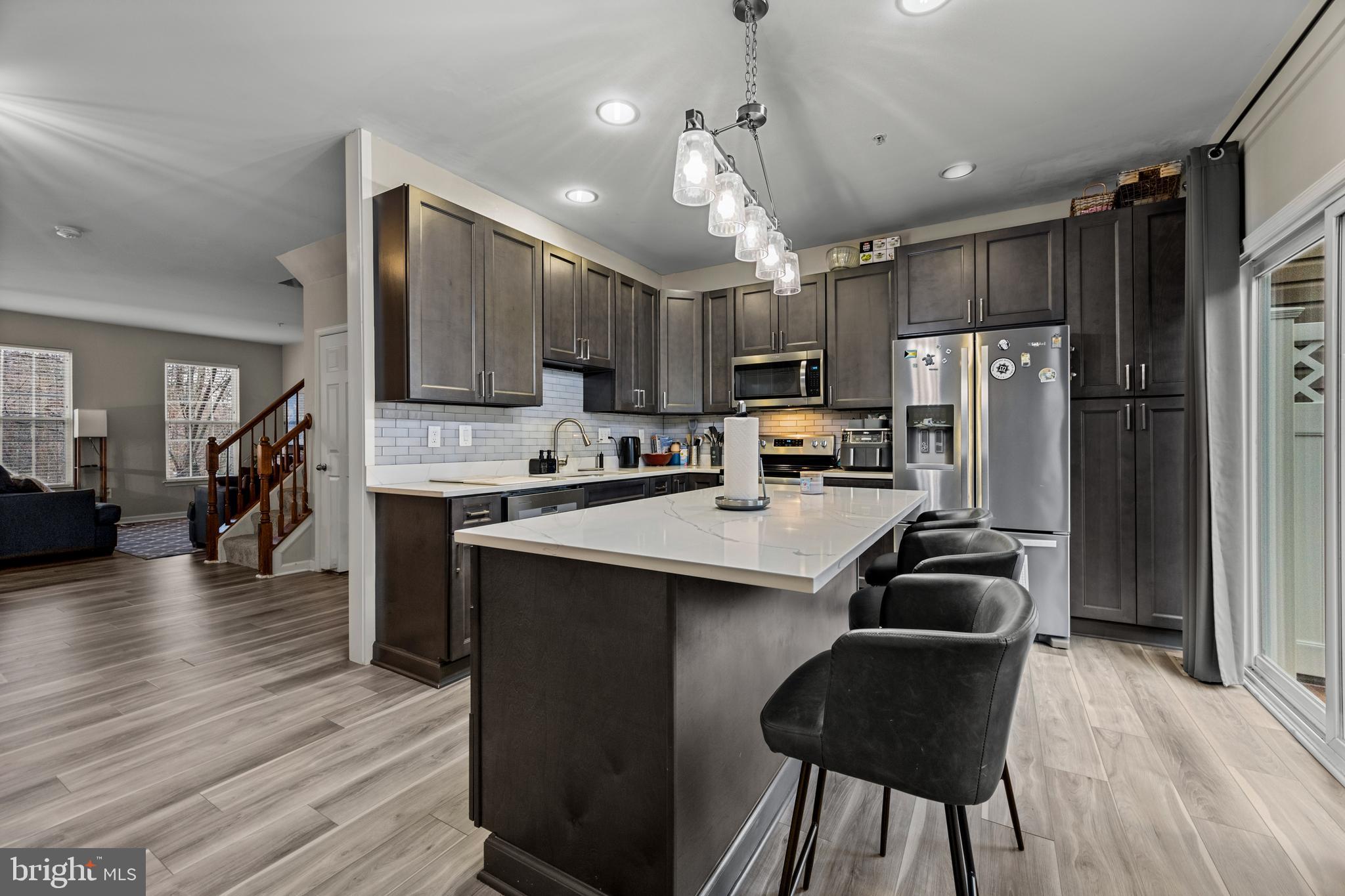 8020 Wright Place Shady Side, MD 20764 - Photo 8 of 21 a kitchen with stainless steel appliances kitchen island granite countertop a refrigerator a stove top oven a sink dishwasher and white cabinets with wooden floor