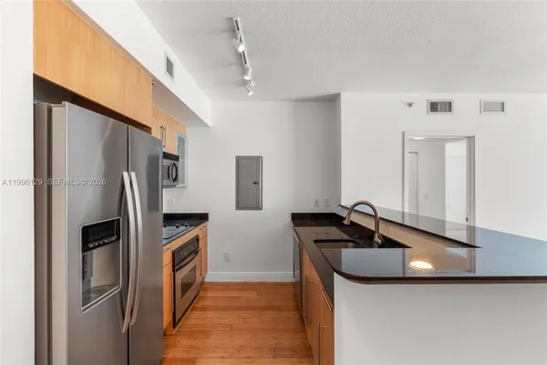 a kitchen with stainless steel appliances granite countertop a sink and a refrigerator