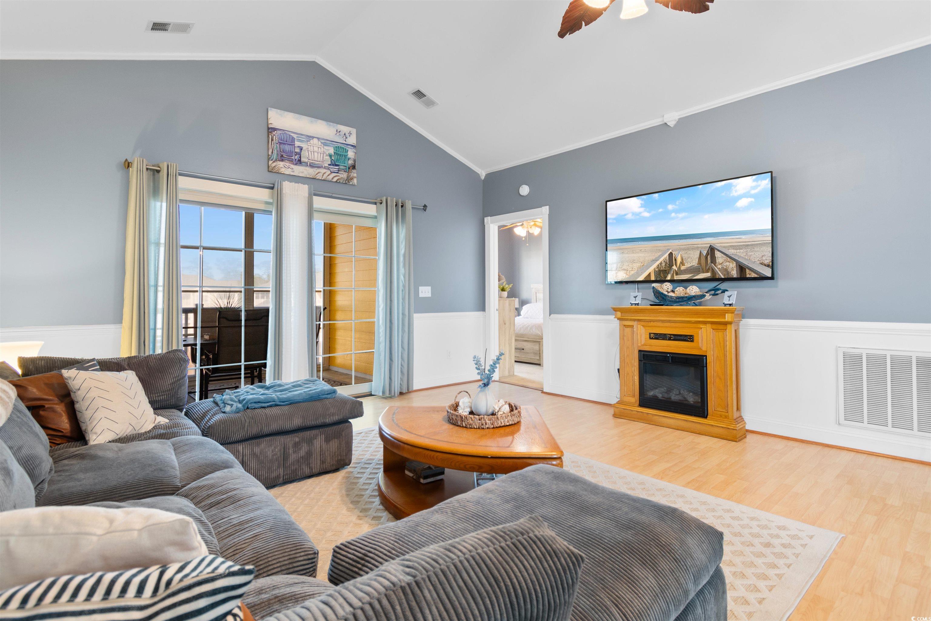 4891 Luster Leaf Circle, Unit 401 Myrtle Beach, SC 29577 - Photo 10 of 35 Living area with a glass covered fireplace, crown molding, a ceiling fan, wood finished floors, and lofted ceiling