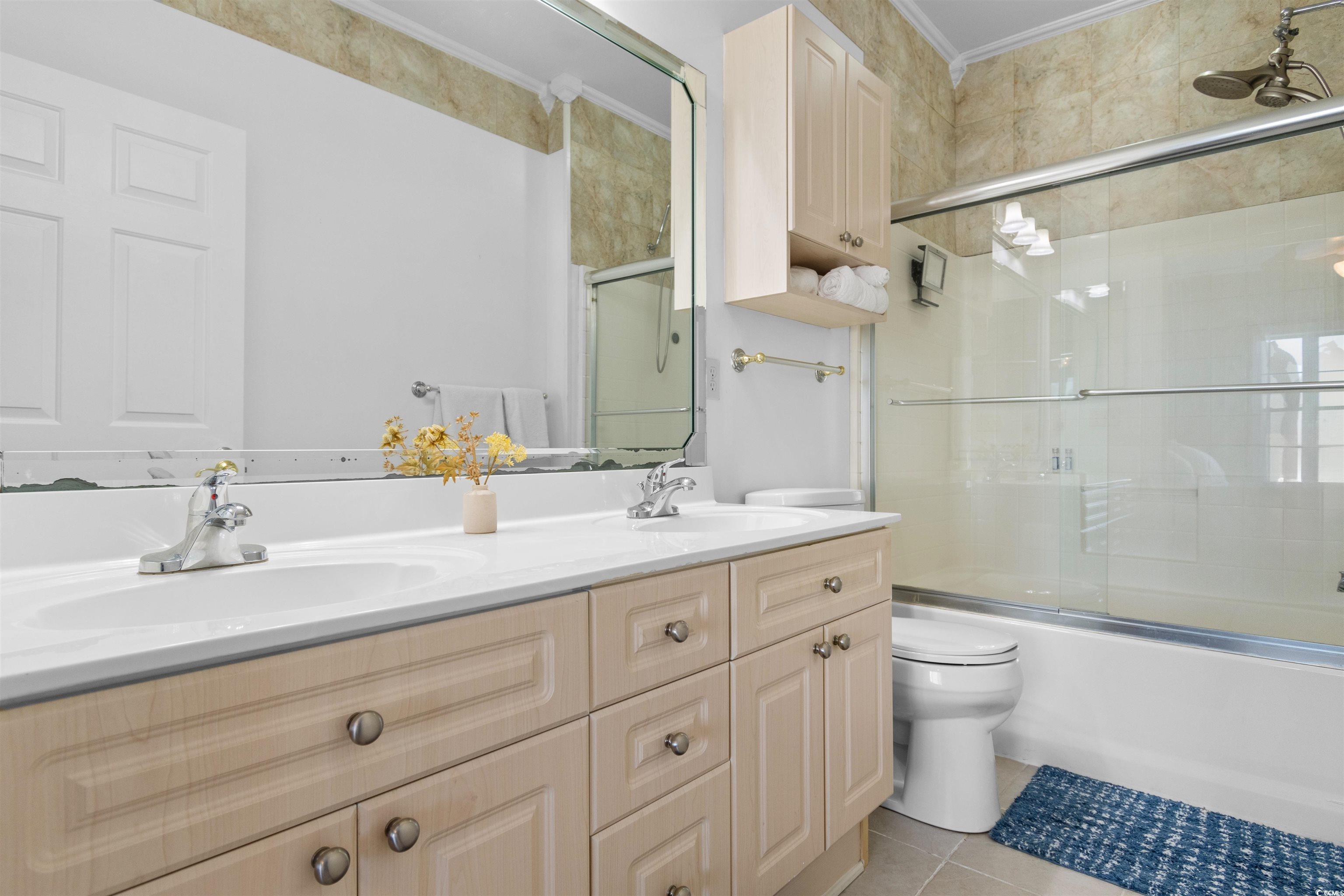 4891 Luster Leaf Circle, Unit 401 Myrtle Beach, SC 29577 - Photo 18 of 35 Bathroom with enclosed tub / shower combo, double vanity, light tile patterned floors, and crown molding