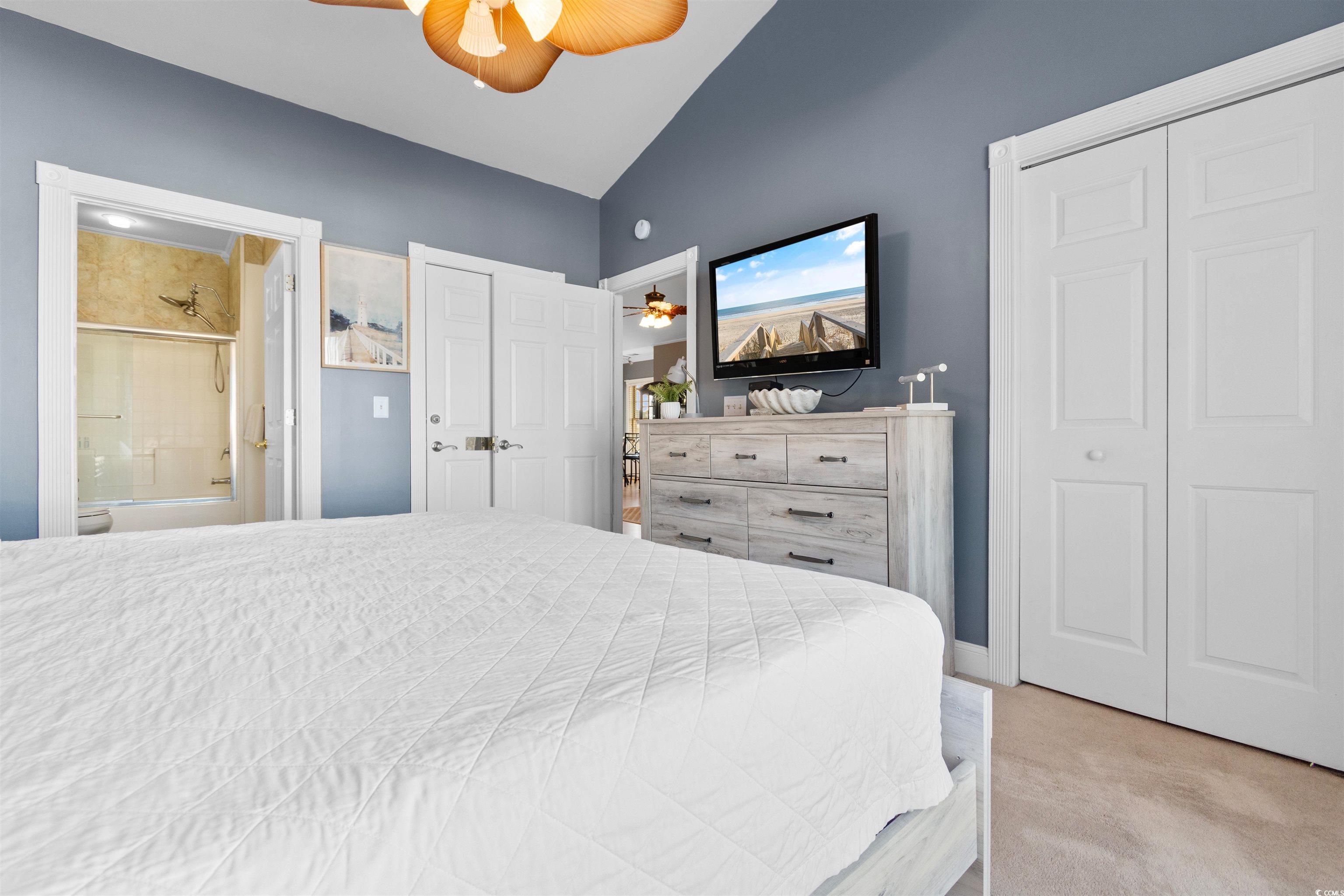 4891 Luster Leaf Circle, Unit 401 Myrtle Beach, SC 29577 - Photo 20 of 35 Carpeted bedroom featuring vaulted ceiling, ensuite bath, and a ceiling fan