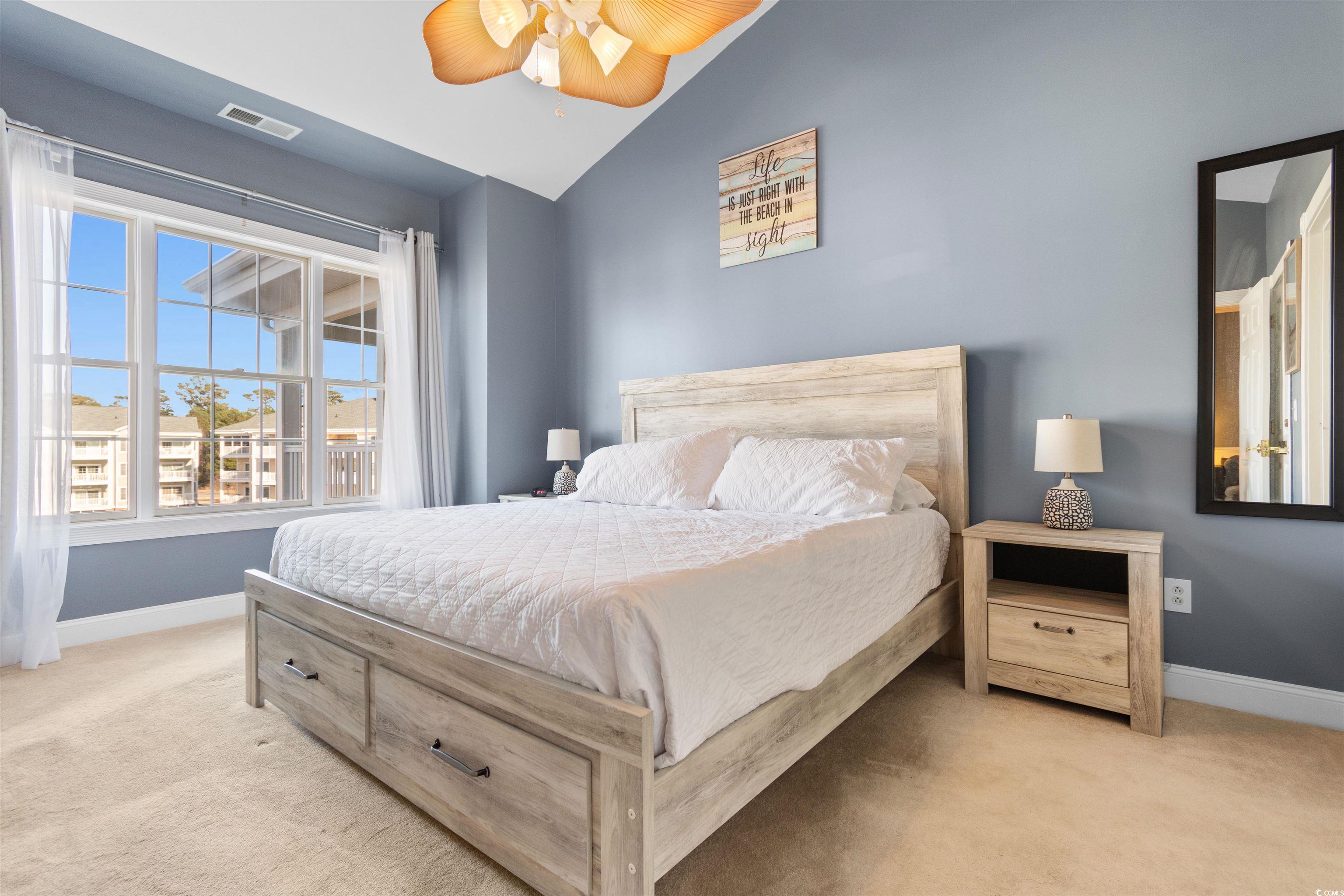 4891 Luster Leaf Circle, Unit 401 Myrtle Beach, SC 29577 - Photo 21 of 36 Bedroom with light colored carpet, ceiling fan, and lofted ceiling