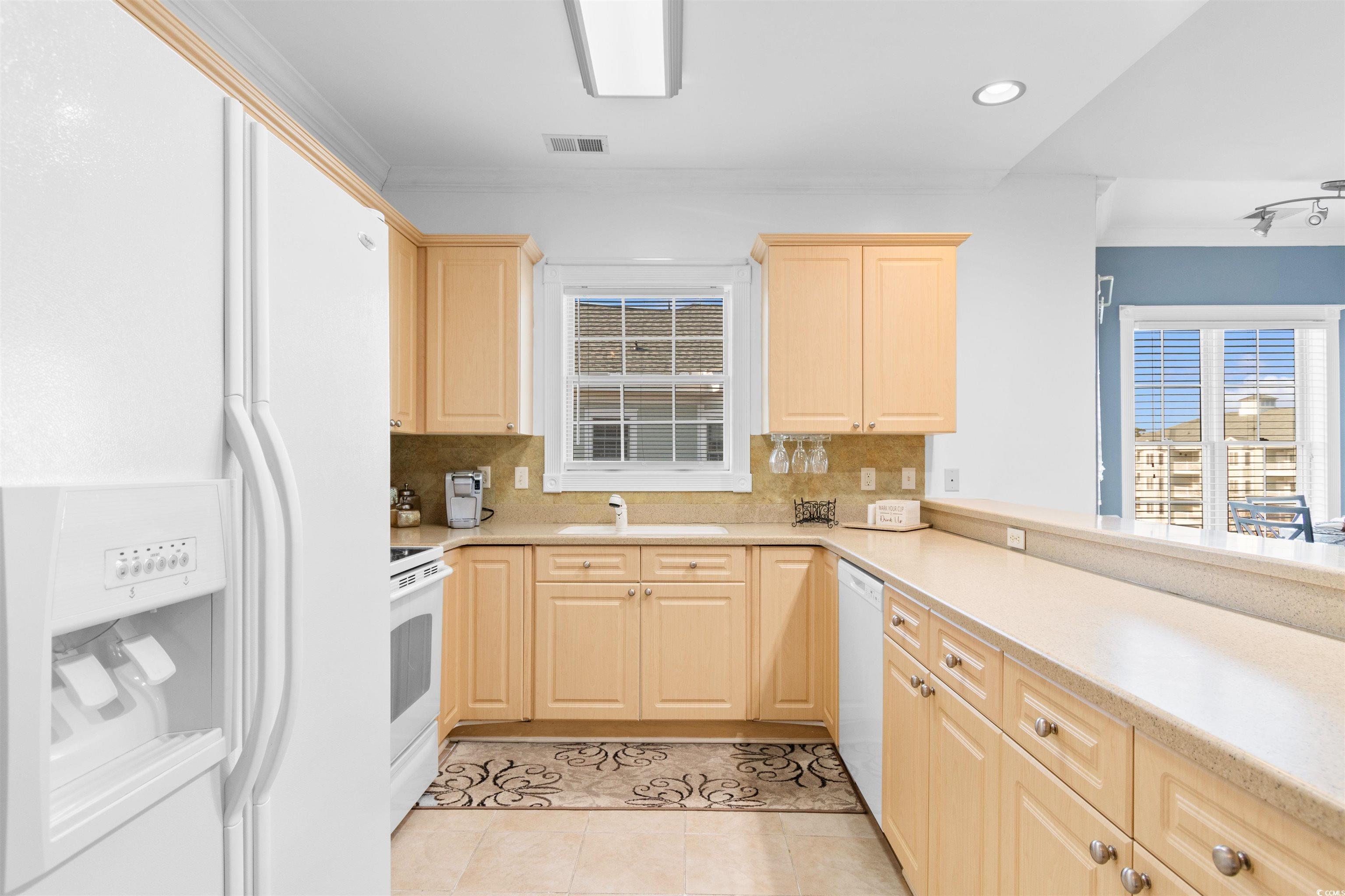 4891 Luster Leaf Circle, Unit 401 Myrtle Beach, SC 29577 - Photo 4 of 35 Kitchen featuring white appliances, light brown cabinetry, tasteful backsplash, recessed lighting, and light tile patterned flooring
