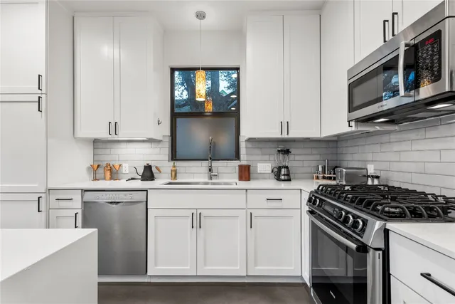 a kitchen with stainless steel appliances granite countertop a sink stove oven and white cabinets with wooden floor
