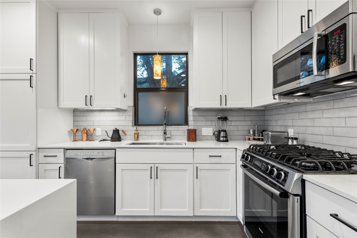1105 East 12th Street Austin, TX 78702 - Photo 4 of 28 a kitchen with stainless steel appliances granite countertop a sink stove oven and white cabinets with wooden floor