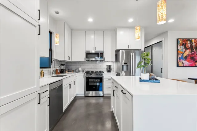 a kitchen with stainless steel appliances a stove sink refrigerator and cabinets