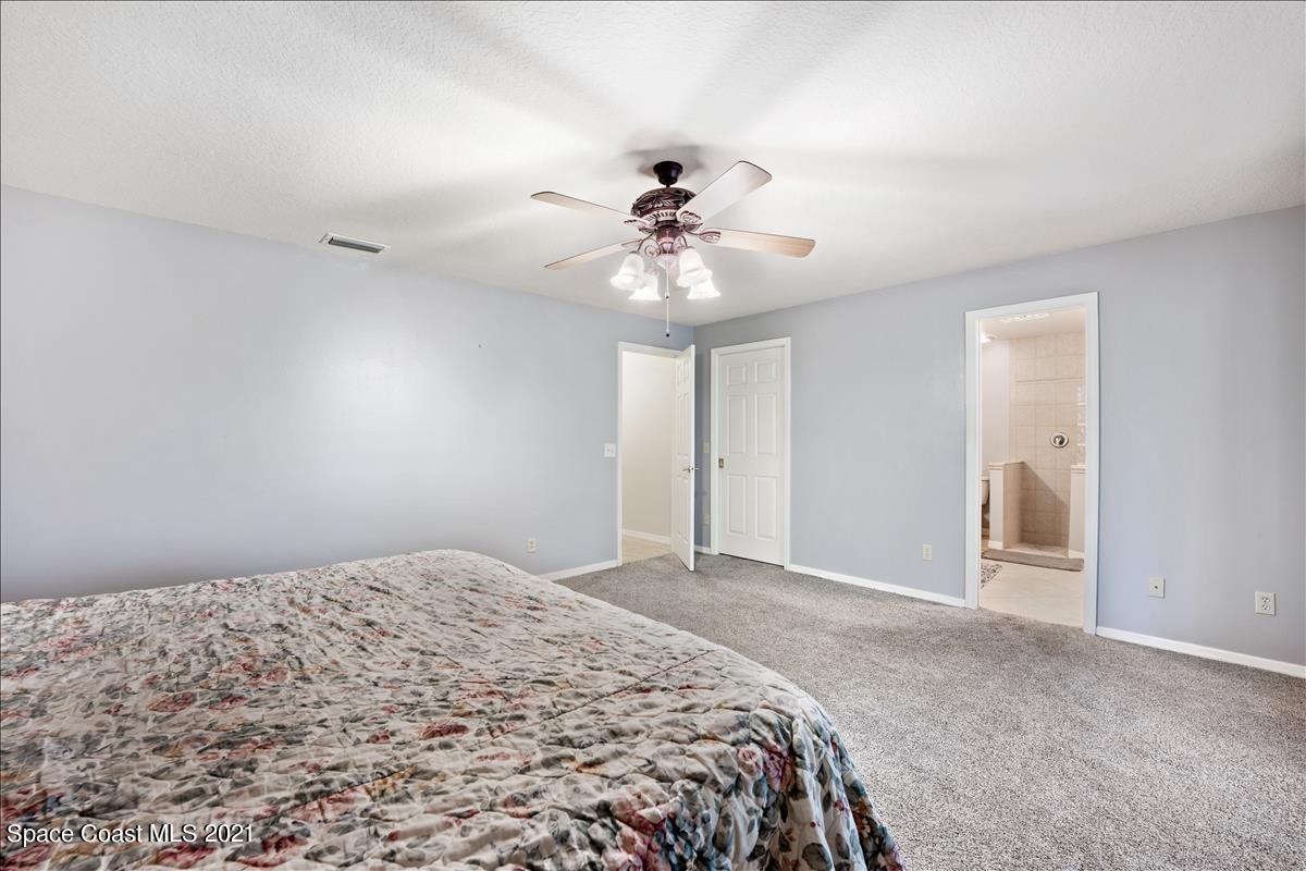 2825 Corey Road Malabar, FL 32950 - Photo 12 of 44 a bedroom with a bed and a chandelier fan