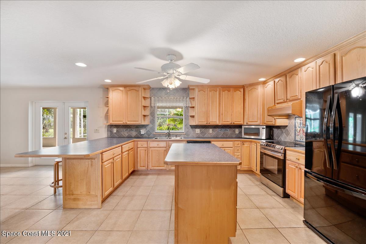 2825 Corey Road Malabar, FL 32950 - Photo 9 of 44 a large kitchen with granite countertop a large counter top stainless steel appliances and cabinets