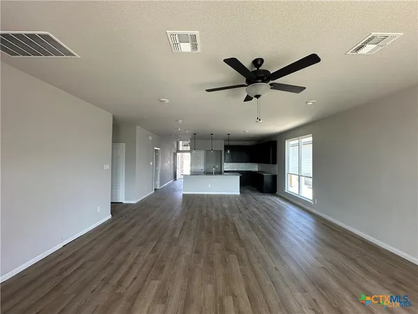 a view of empty room with wooden floor and ceiling fan