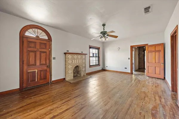 a view of empty room with fireplace and wooden floor