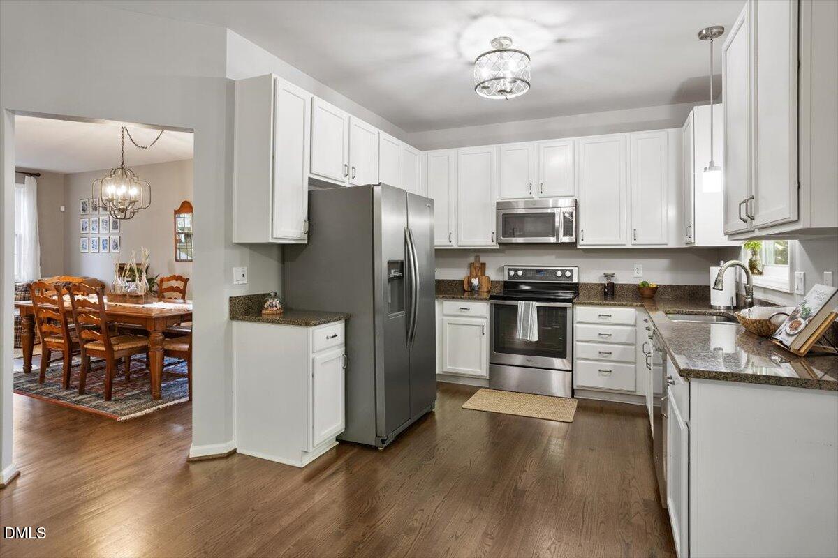 2220 Spruce Shadows Lane Raleigh, NC 27614 - Photo 8 of 29 a kitchen with granite countertop a refrigerator a stove top oven a sink dishwasher and white cabinets with wooden floor