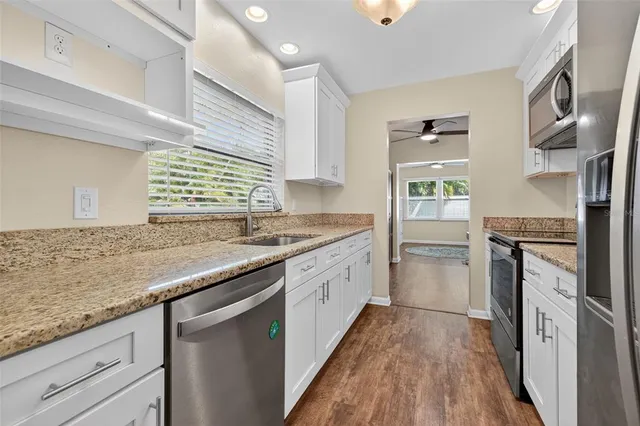 a kitchen with granite countertop stainless steel appliances a sink stove top oven and cabinets