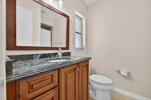 a bathroom with a granite countertop toilet sink and mirror