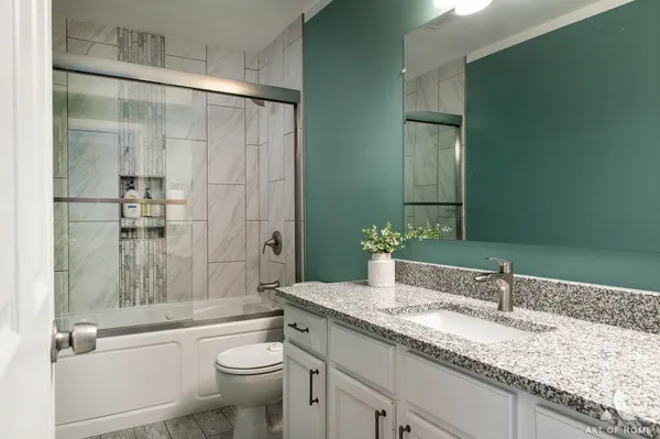 a bathroom with a granite countertop sink a toilet and shower