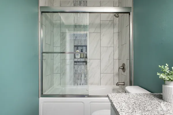 a bathroom with a granite countertop sink and shower
