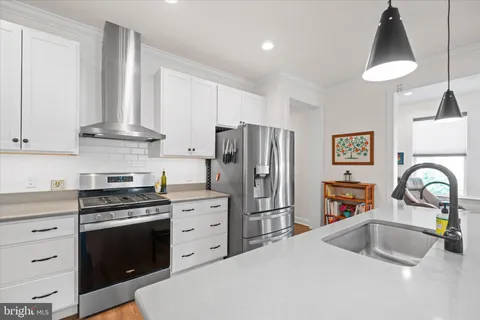 a kitchen with stainless steel appliances a stove a sink a refrigerator and a stove with white countertops