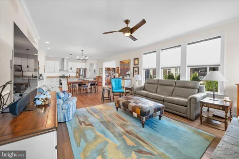 a living room with furniture kitchen view and a wooden floor