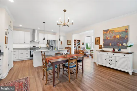a kitchen with stainless steel appliances kitchen island granite countertop a table chairs and white cabinets