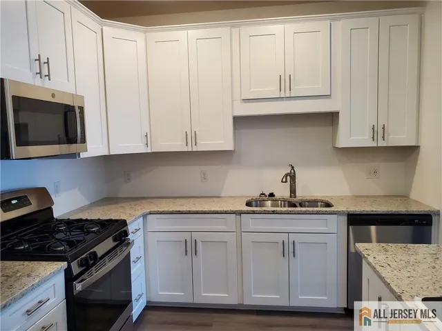 a kitchen with granite countertop white cabinets and stainless steel appliances