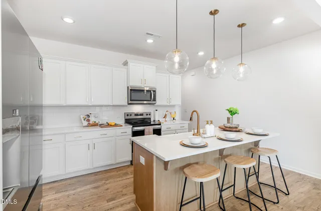 a kitchen with stainless steel appliances granite countertop a refrigerator a sink dishwasher a stove a dining table and chairs