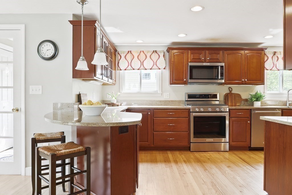 18 Moore Street Natick, MA 01760 - Photo 12 of 42 a kitchen with stainless steel appliances granite countertop a stove top oven a sink a dining table and chairs with wooden floor