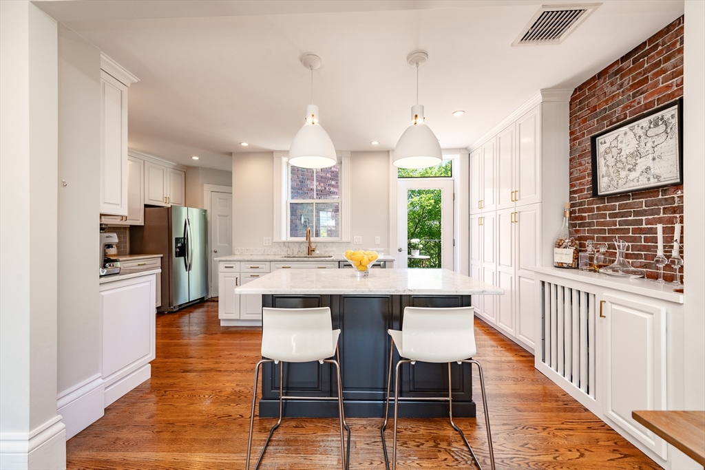 13 Harvard Street, Unit 3 Boston, MA 02129 - Photo 2 of 14 a kitchen with stainless steel appliances a dining table chairs refrigerator and sink
