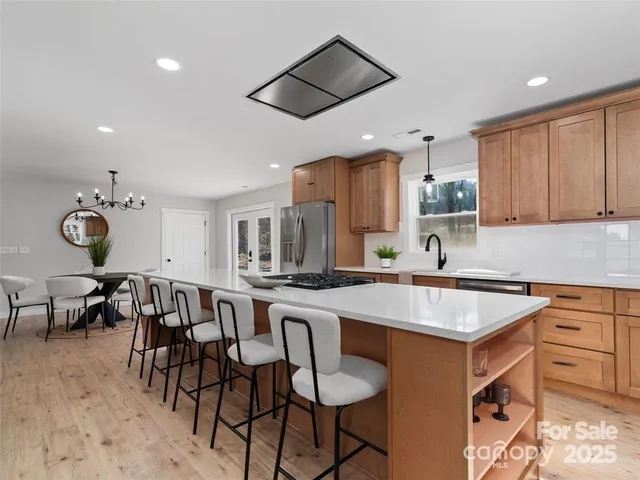 a kitchen with stainless steel appliances granite countertop a table chairs sink and cabinets