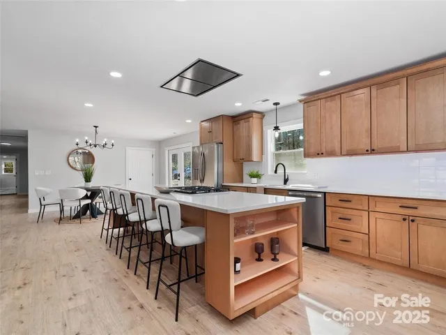 a kitchen with kitchen island granite countertop a table chairs sink and cabinets