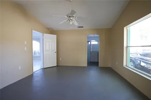 an empty room with chandelier fan and windows