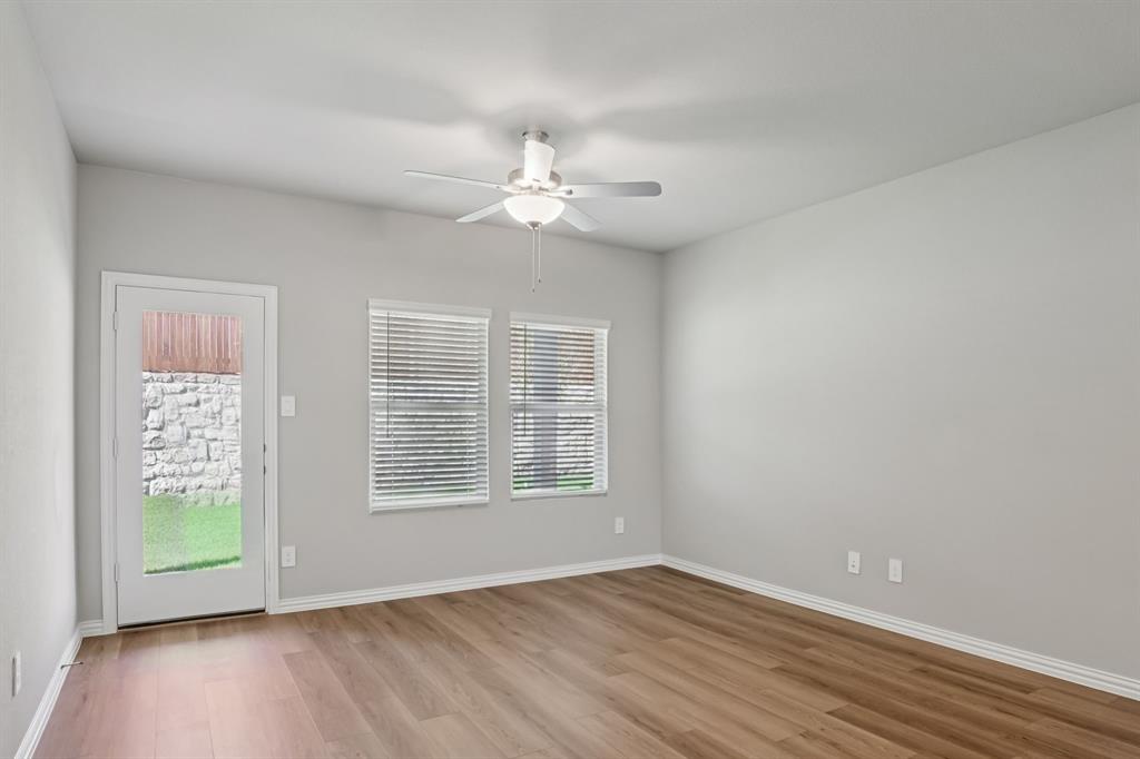 1725 Arches Road Anna, TX 75409 - Photo 13 of 28 an empty room with wooden floor chandelier fan and windows