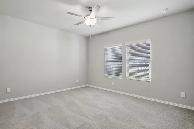 an empty room with a window and a ceiling fan